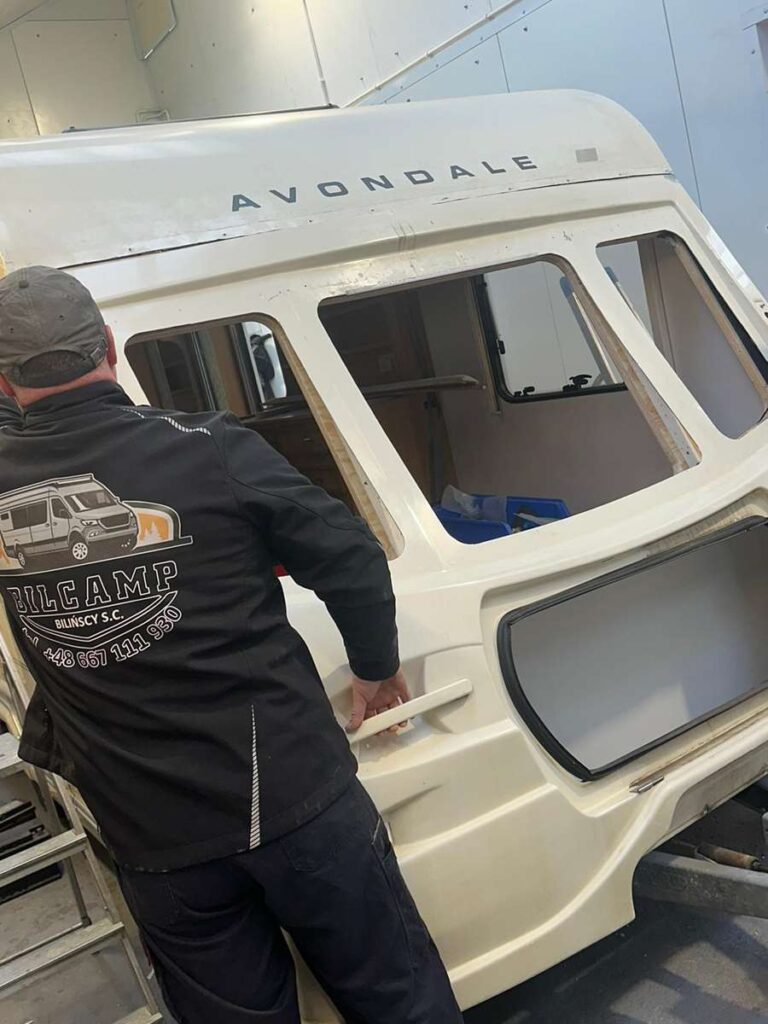 mechanik w trakcie prac naprawczych przyczepy kempingowej
